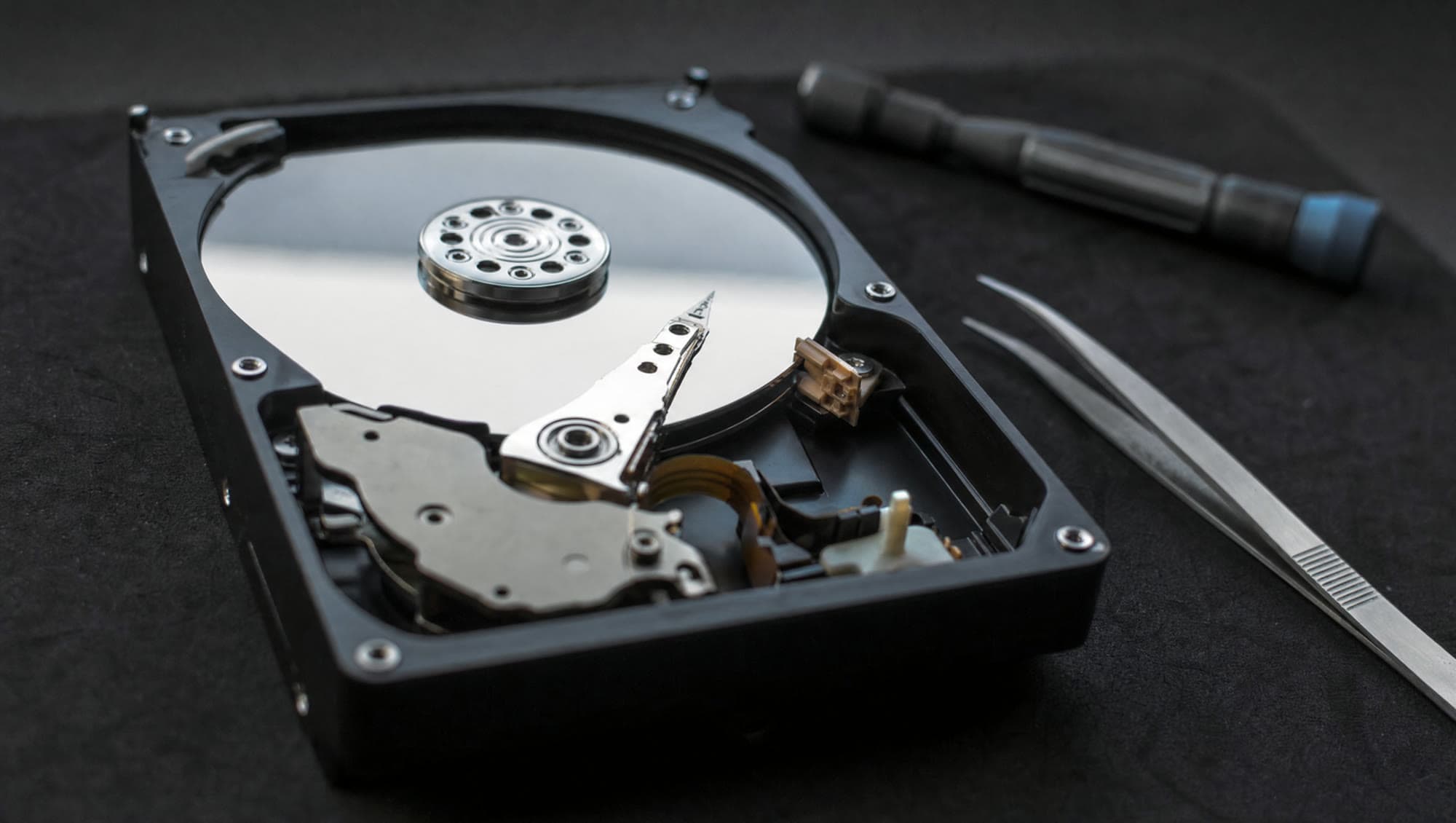 An opened hard drive on an anti-static mat, platters catching the bench light.