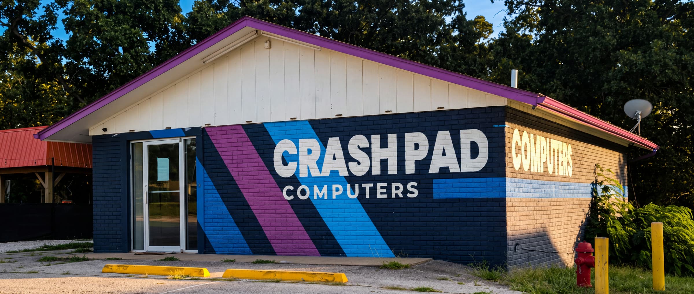 The Crash Pad Computers building on Route 5 — navy brick with the painted stripe mural and CRASH PAD COMPUTERS lettering across the front.